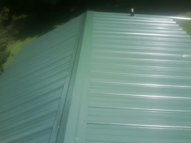 New green metal panels meeting at the ridge of a roof — Flat Roof Repair work by our crew in Kelford
