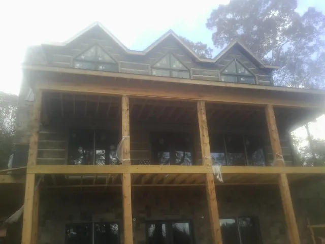 Dormers and porch framing on a large log home under construction — Roof Coating work by our crew in Kelford