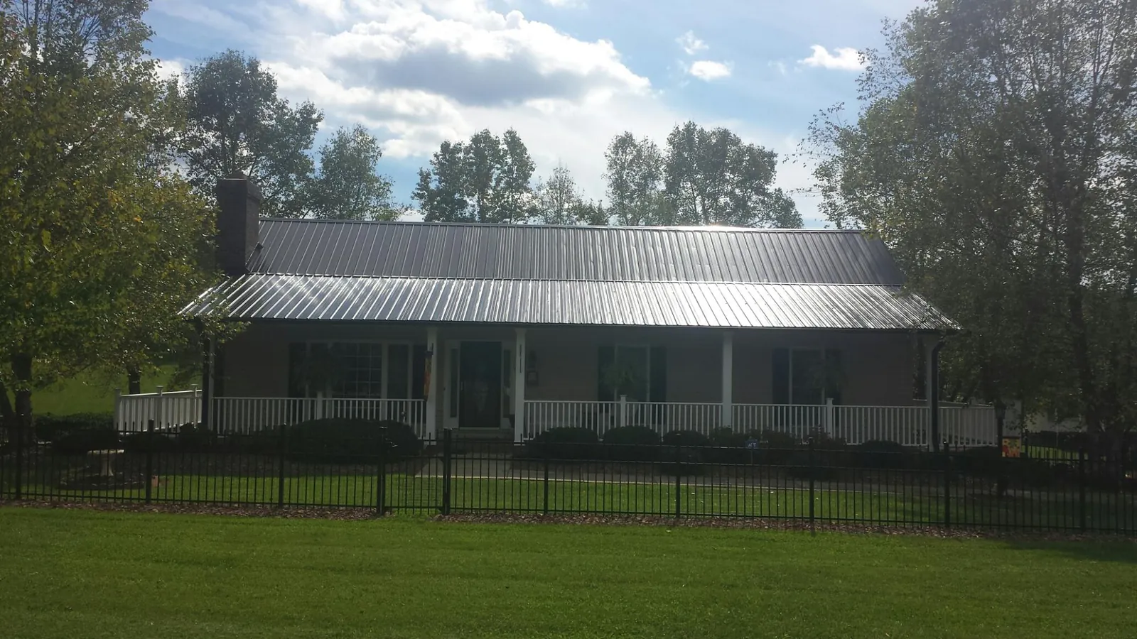 Gray metal roof on a brick ranch with a full width front porch — Gutter Guard Installation work by our crew in Kelford
