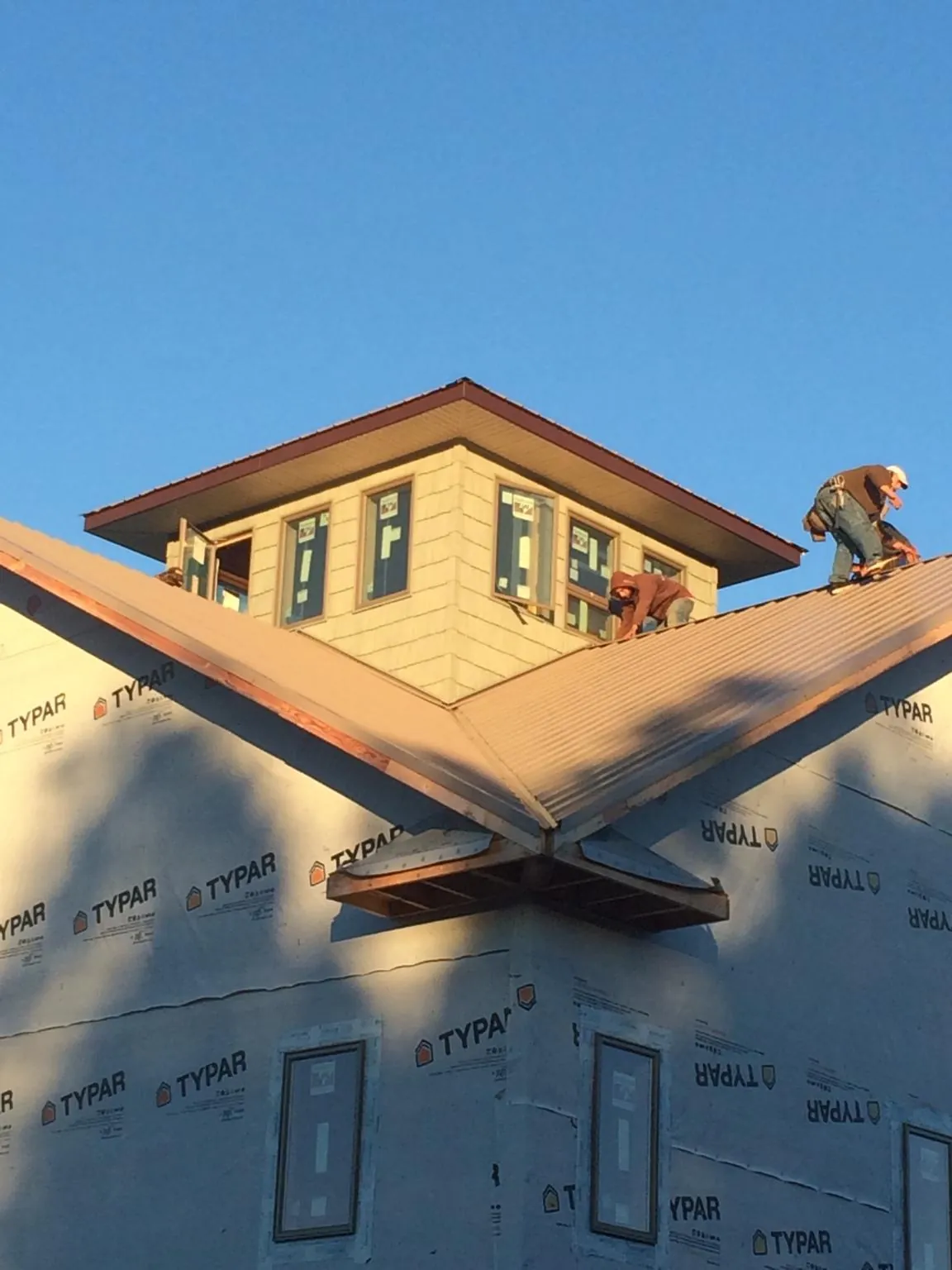 Roofers working around a rooftop cupola on a new metal roof at sunset — Roof Waterproofing in Kelford by Roofing Brothers